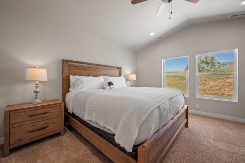 a bedroom with a large bed and two windows at Wasatch Peak Chateau Unit A with Pool and Hot Tub in Mountain Green