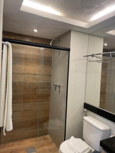 a bathroom with a toilet and a glass shower at Praia do canto Apart Hotel - Apto 203 Varanda Lateral com Vista Mar in Vitória