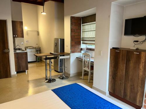 a room with a kitchen with a table and a television at Amoblados Medellín Laureles in Medellín