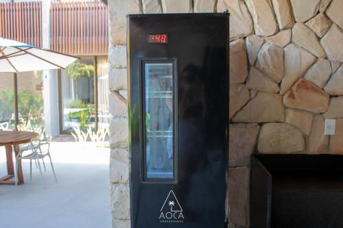 a black phone booth next to a stone wall at Villa Naluri - Seu Refúgio a 50 metros da praia em Japaratinga in Japaratinga