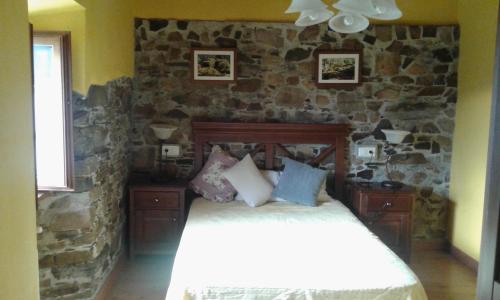 a bedroom with a stone wall with a bed at La casa de atrás in Arancedo