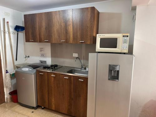 a kitchen with a refrigerator and a microwave at Amoblados Medellín Laureles in Medellín