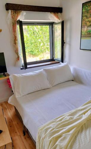 a bed with white sheets in a room with a window at Sweet Home Aria in Çorovodë