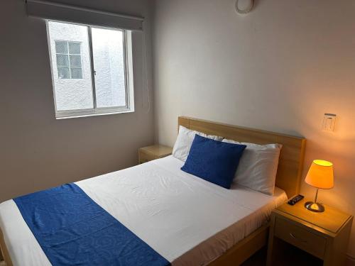a bedroom with a bed with a blue pillow and a window at Amoblados Medellín Laureles in Medellín