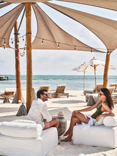 a man and woman sitting on chairs on the beach at Etéreo, Auberge Collection in Playa del Carmen