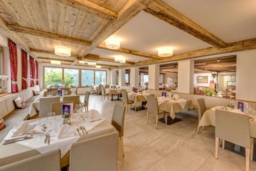 un restaurant avec des tables blanches, des chaises et des fenêtres dans l'établissement Hotel Alpenland, à Moso in Passiria