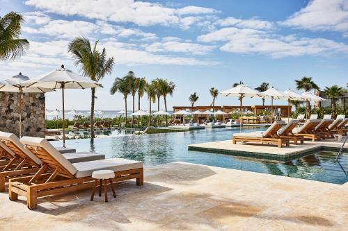 a pool with lounge chairs and umbrellas at a resort at Etéreo, Auberge Collection in Playa del Carmen