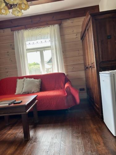 a living room with a red couch and a window at Leśne PoBudki in Białowieża