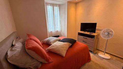 a bedroom with an orange bed with pillows and a fan at Maison de village in Stazzona