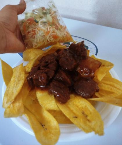 a plate of food with chips and a slice of pizza at Mel Homespot in Managua