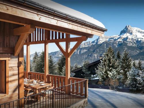 Una terraza de madera con una mesa y montañas al fondo. en Chalet Galata - OVO Network, en Combloux