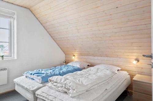 two beds in a room with a wooden wall at 0381-Romo-Sonder-Frankel-44 in Havneby