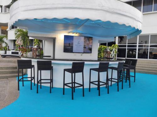 a bar with chairs and a table with an umbrella at Aquarius Hotel Boutique in Pampatar