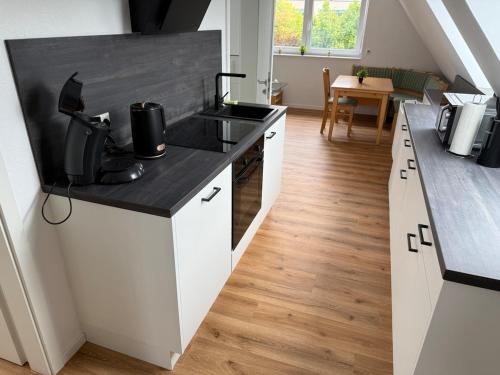 a kitchen with white cabinets and a black counter top at New in 2025 - Anholter vacation apartment in Isselburg