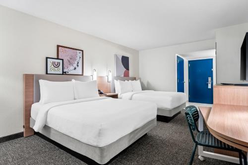 a hotel room with two beds and a desk at Spark by Hilton Orlando near Universal in Orlando