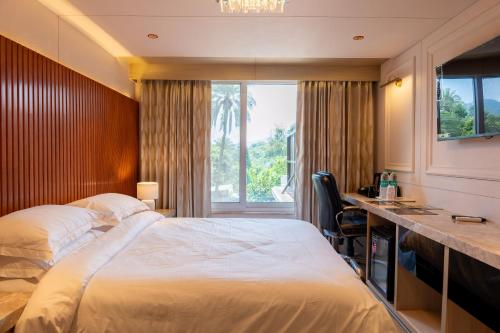 a hotel room with a bed and a desk and a window at Chacha Inn The Garden Retreat in Mount Ābu