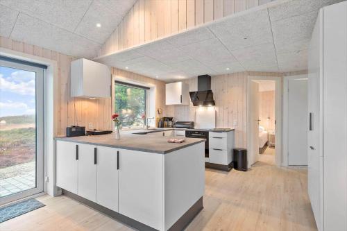 a kitchen with white cabinets and a large window at 0180-Romo-Ejnar-Mikkelsensvej-8 in Lakolk