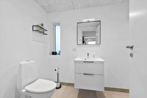a white bathroom with a toilet and a sink at 0180-Romo-Ejnar-Mikkelsensvej-8 in Lakolk