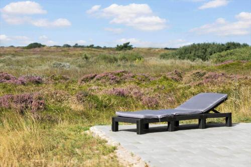 a black bench sitting on a path in a field at 0180-Romo-Ejnar-Mikkelsensvej-8 in Lakolk