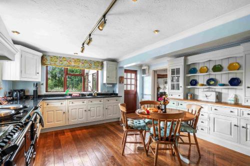 a kitchen with white cabinets and a table with chairs at Churchill Country Retreat By My Getaways in Lewes