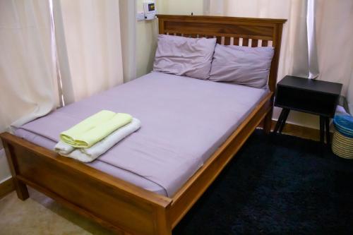a bed with a wooden frame with a yellow towel on it at Spacious 2 bedroom home with equipped kitchen in Dar es Salaam