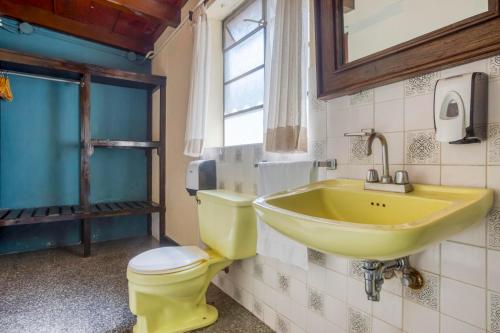a bathroom with a yellow sink and a toilet at Socialtel Atitlan in Panajachel