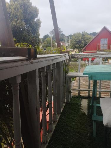 a porch with a blue table and a red barn at Habitación El Jardín Secreto in Isla Negra