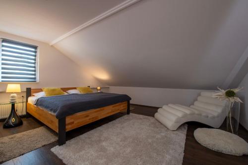 a bedroom with a bed and a white chair at Apartmány Ztracená in Roudnice nad Labem