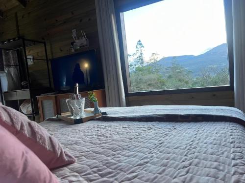 a bedroom with a bed with a large window at Tiny House Canjerana in Praia Grande