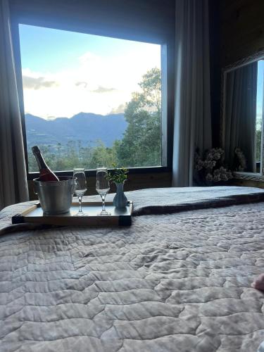 a bed with two glasses and a tray on it with a window at Tiny House Canjerana in Praia Grande