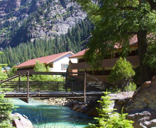 a bridge over a river in front of a cabin at Hot Springs Inn in Ouray