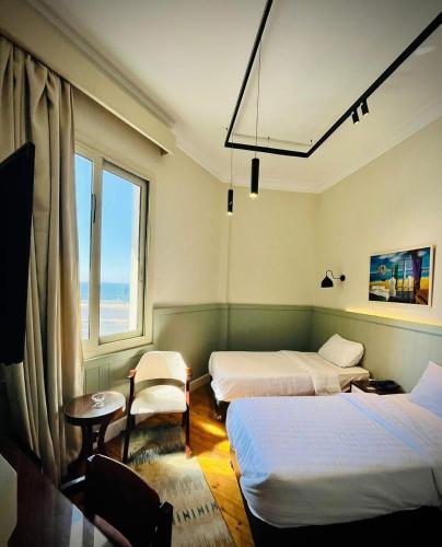 a hotel room with three beds and a window at Ritz hotel in Alexandria