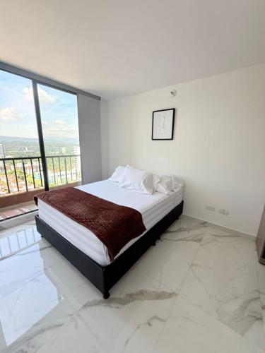 a white bedroom with a bed with a large window at apartamento amoblado en la foscal in Floridablanca