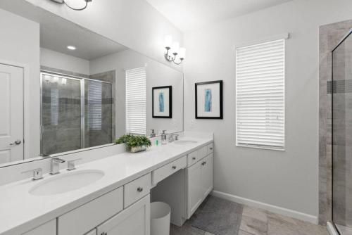 une salle de bain blanche avec deux lavabos et une douche dans l'établissement Ultimate 8br Family Getaway, à Kissimmee