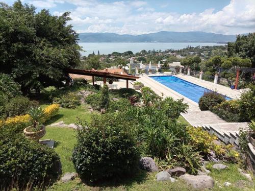 a swimming pool in a garden with a view of the water at Casa Vinca in San Juan Cosalá