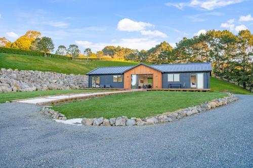 a house on a hill with a gravel driveway at Stunning Modern Hillside Haven near Pukekohe in Bombay