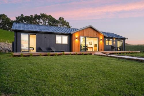 a house with a solar roof on a lawn at Stunning Modern Hillside Haven near Pukekohe in Bombay