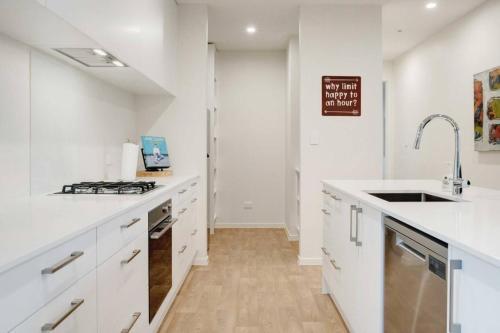 a white kitchen with a sink and a stove at Stunning Modern Hillside Haven near Pukekohe in Bombay