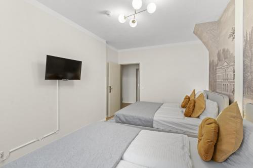 a bedroom with two beds and a flat screen tv at Votivpark Rooms I Self Check In in Vienna