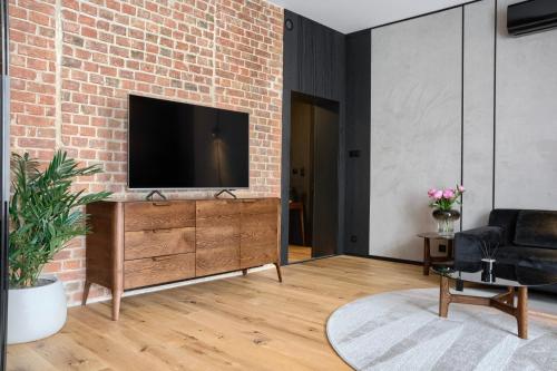 a living room with a television on a brick wall at Apartamenty Chełmińskie in Chełmno