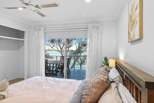 a bedroom with a bed and a view of the ocean at Lakefront Peace and Relaxation in Budgewoi