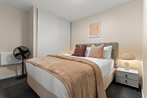 オークランドにあるGorgeous Abode With Pool and Parking near SkyTowerの白いベッドルーム(大型ベッド1台、ファン付)