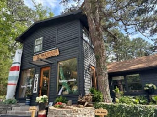 a black house with a tree in front of it at Adventure Cabin 3 King Bed Hot Tub in Eureka Springs