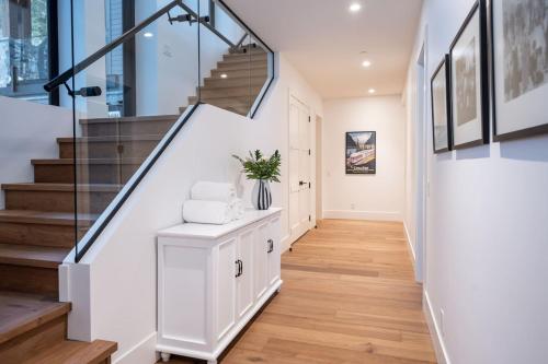 a hallway with a staircase with white walls and wood floors at Sitka Spruce Mountain Chalet in Revelstoke