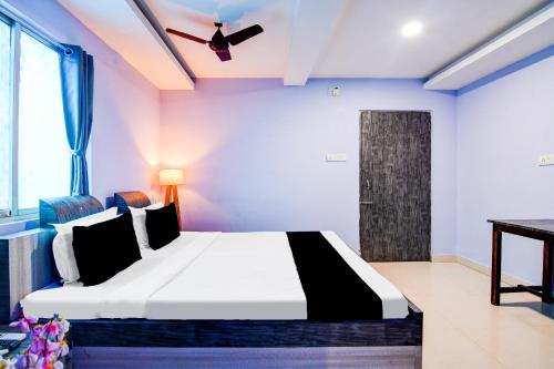 a bedroom with a bed and a ceiling fan at Hotel O The Lord Jagannath Guest House in Puri