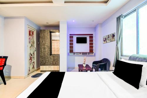a bedroom with a bed and chairs and a window at Hotel O The Lord Jagannath Guest House in Puri