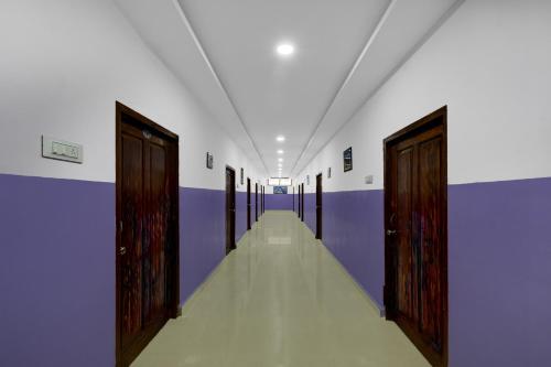 an empty corridor with wooden doors in a room at Hotel O P R S Elite in Surūrnagar