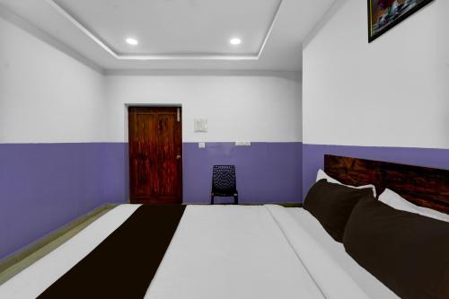 a bedroom with a large bed and a chair at Hotel O P R S Elite in Surūrnagar