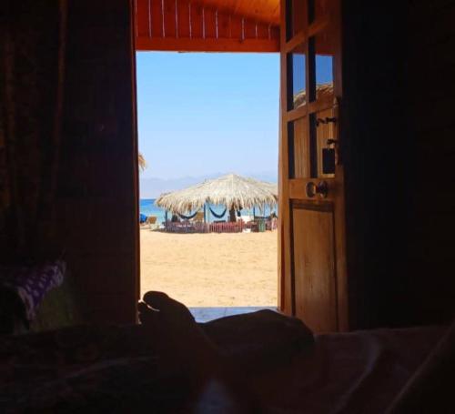 an open door to a beach with an umbrella at Soul camp in Nuweiba‘ el Muzeinah