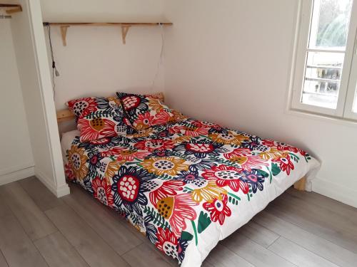 Una cama con un edredón colorido en un dormitorio. en Gîte du rocher d'argout, en Noisy-sur-École